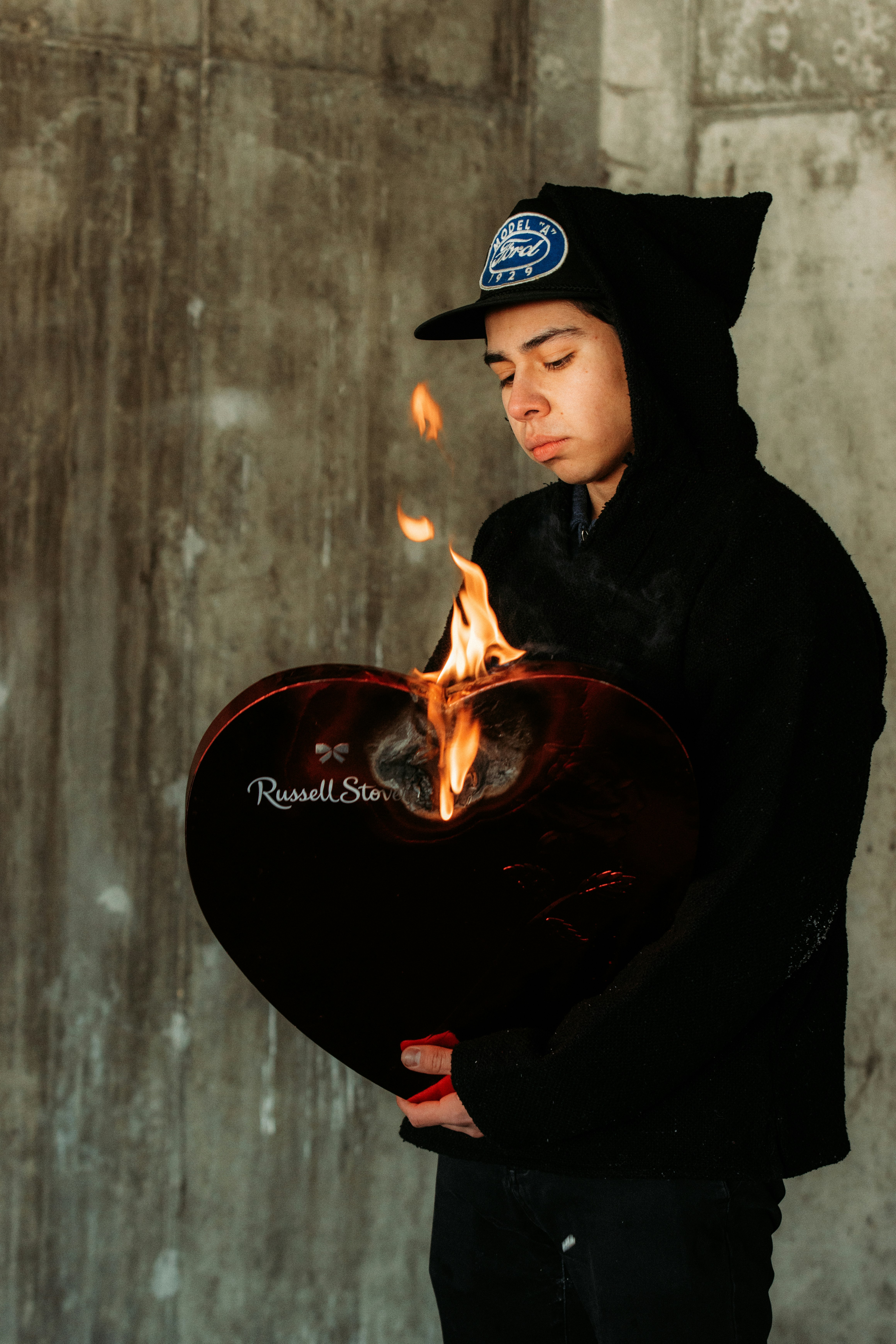 man in black hoodie and black hat holding fire